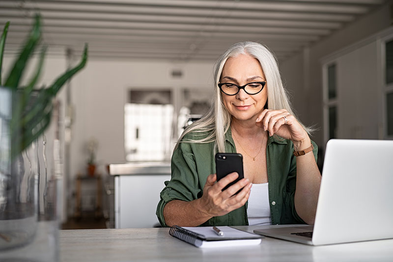 iStock-1161412866 Woman using her phone to manage her bank account